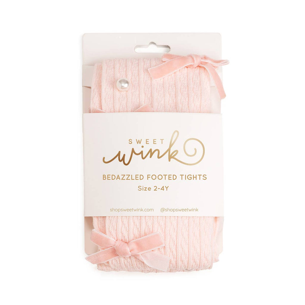 Packaged pink bedazzled footed tights with a bow on a white background, featuring the brand 'Sweet Wink'.