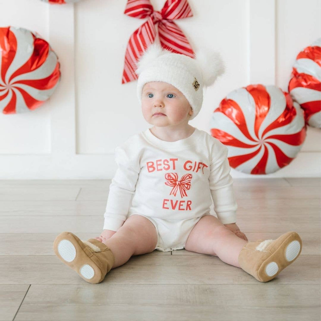 Baby wearing a 'Best Gift Ever' outfit with candy-themed decorations