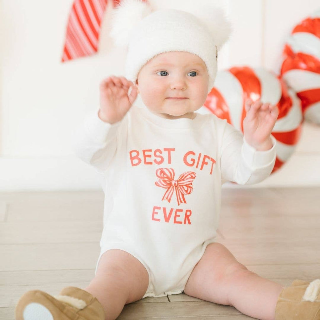 Baby wearing a 'Best Gift Ever' onesie with candy canes in the background