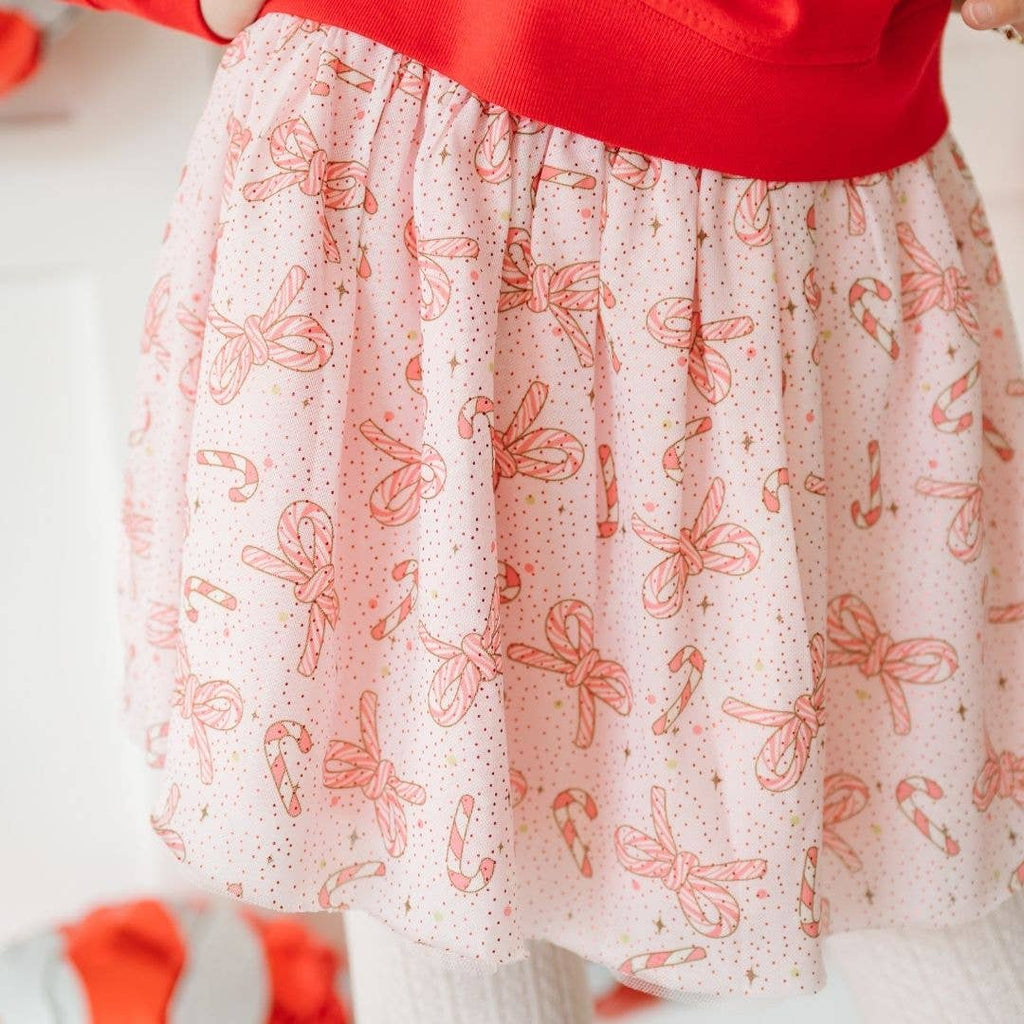 Skirt with candy cane and bow pattern worn by a person in a red top.