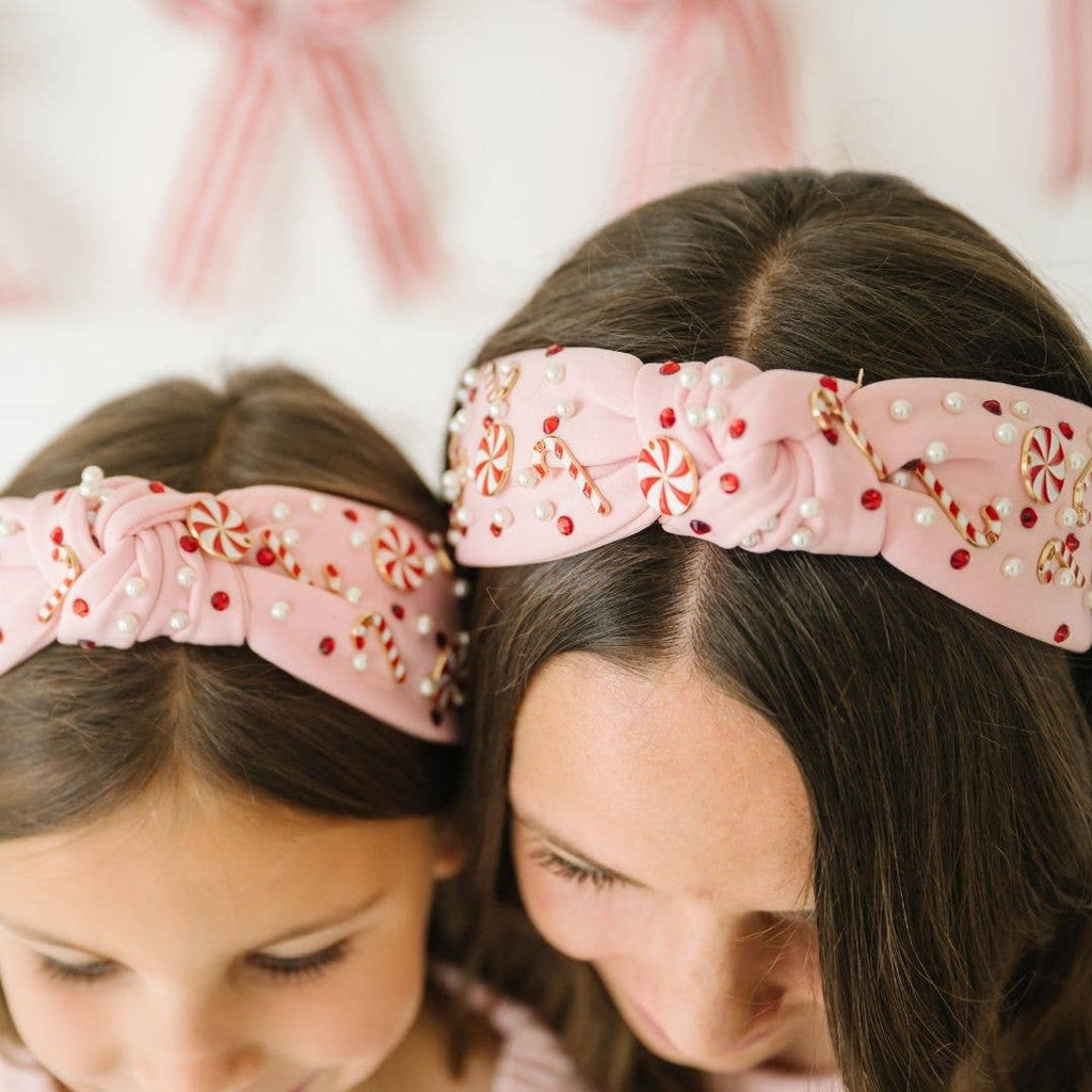 Two children wearing pink headbands with decorative elements.