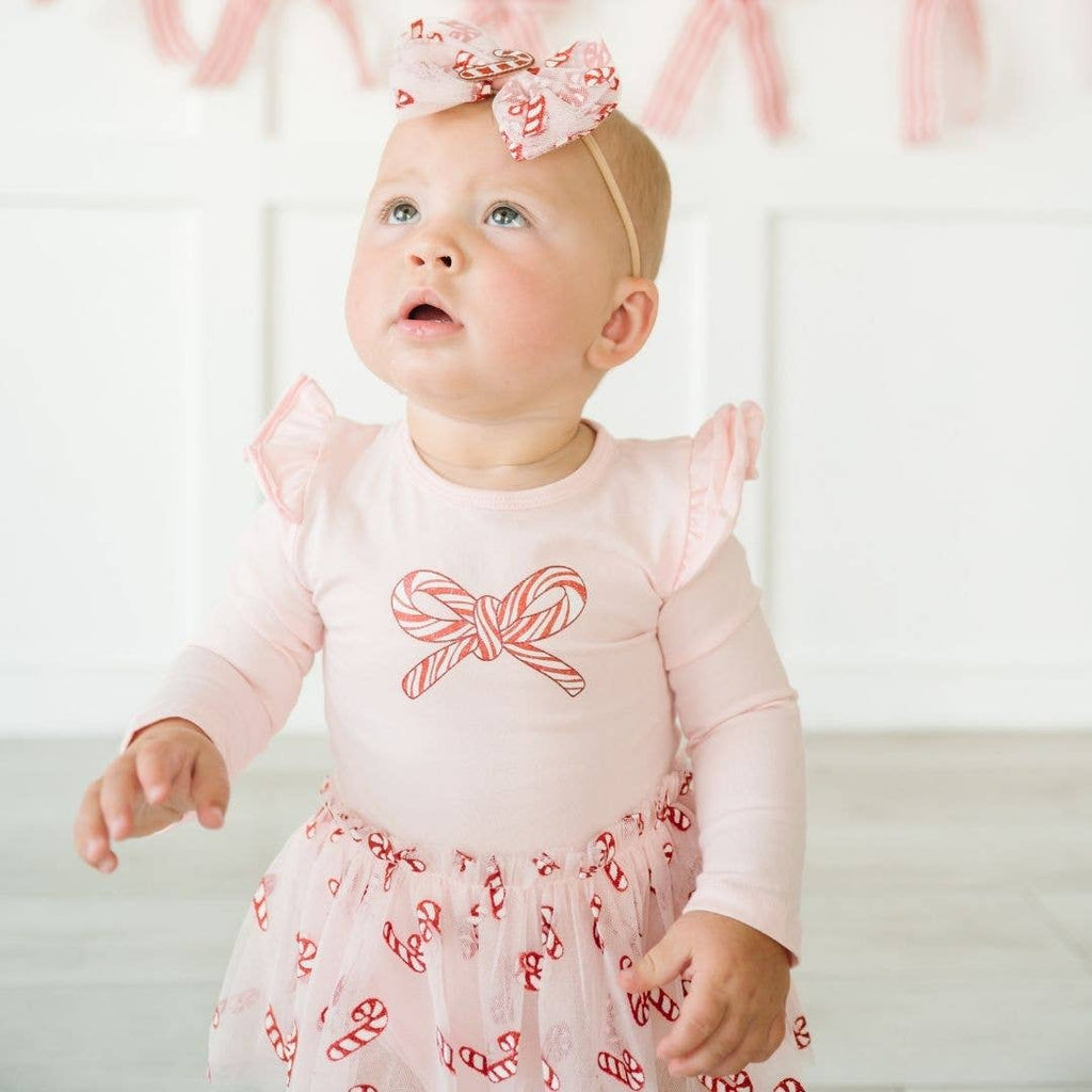 Baby wearing a pink dress with red bow design and matching headband.