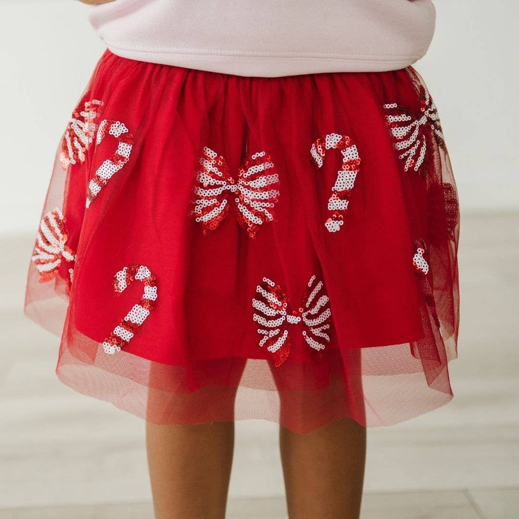 Red skirt with candy cane patterns worn by a person on a plain background