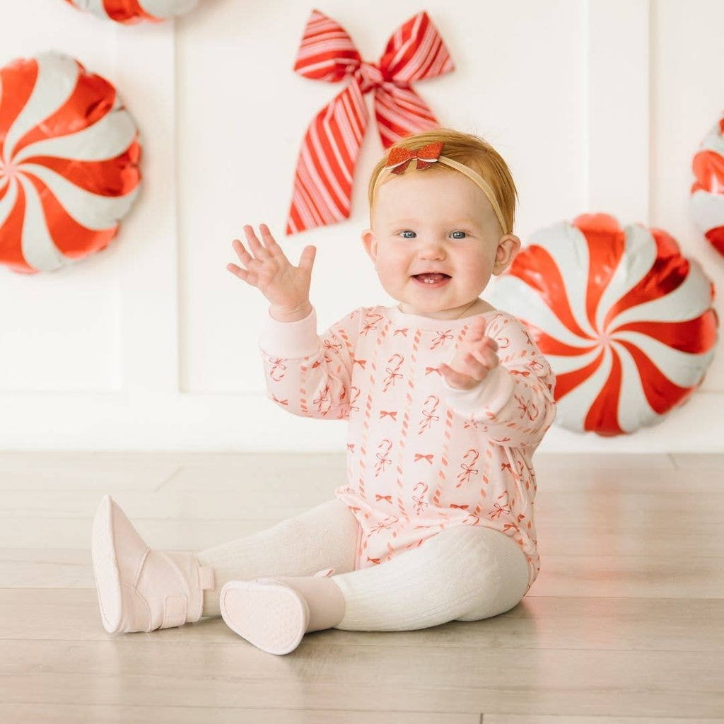Baby sitting on the floor with candy-themed decorations in the background
