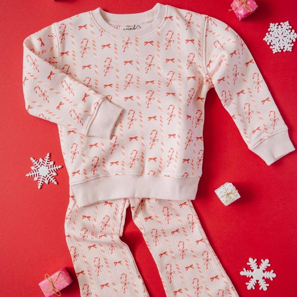Children's pajama set with candy cane and bow pattern on a red background with snowflakes and gift boxes.
