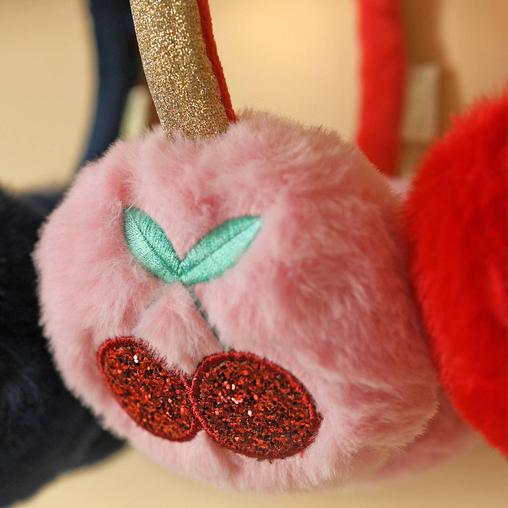 Close-up of a plush toy with pink fur, red glittery accents, and green leaves.
