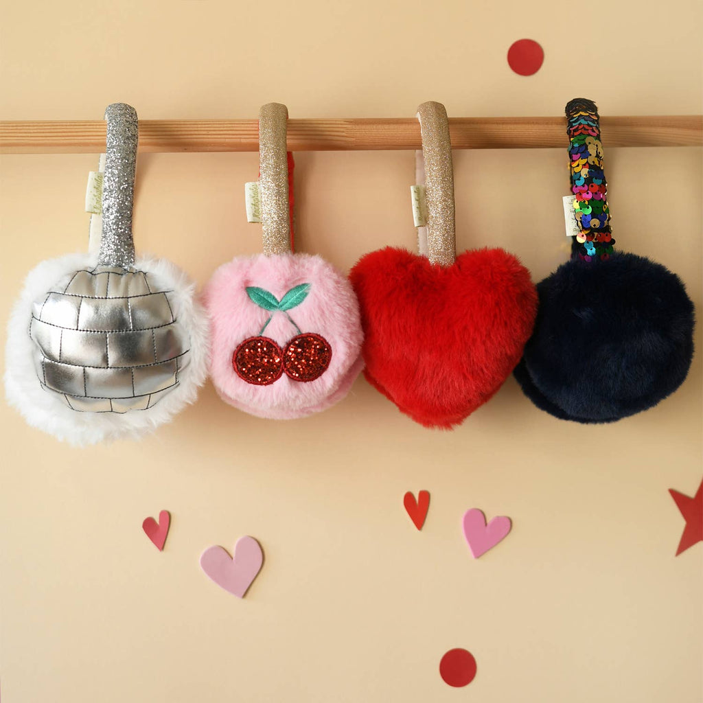Four colorful keychains hanging on a wooden rod with decorative hearts and stars on a beige background.