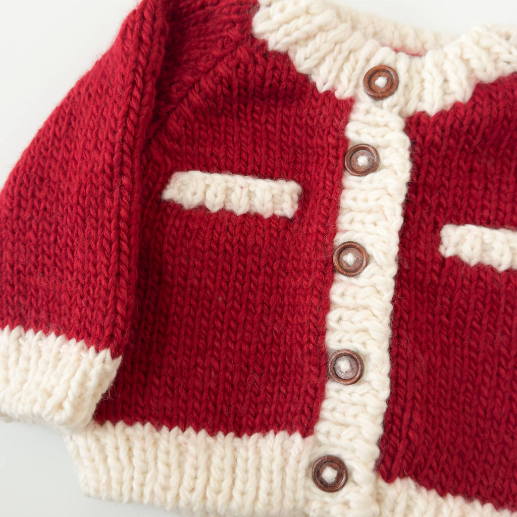 Red and white knitted cardigan with buttons on a light gray background