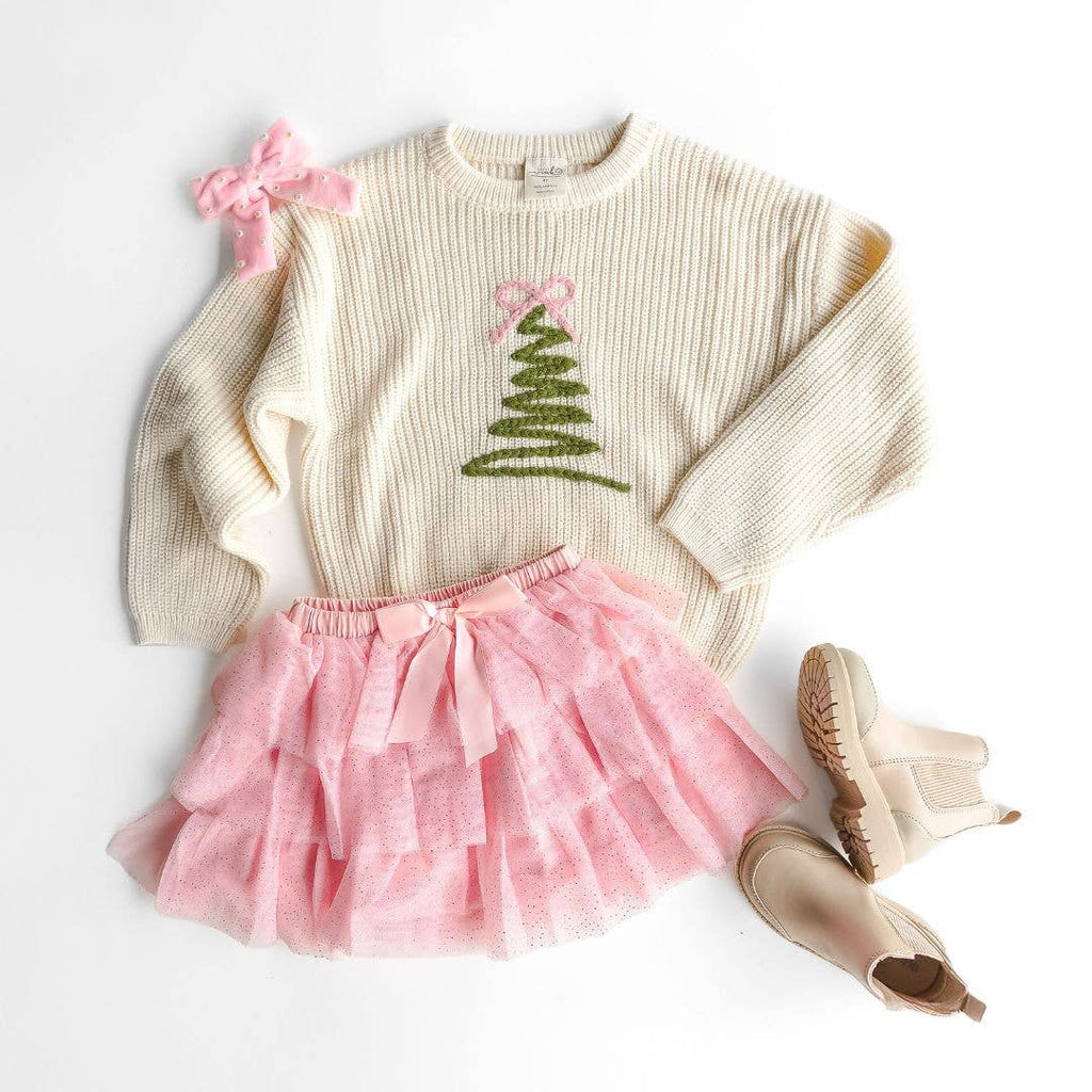 Children's outfit with sweater, pink skirt, and boots on a white background