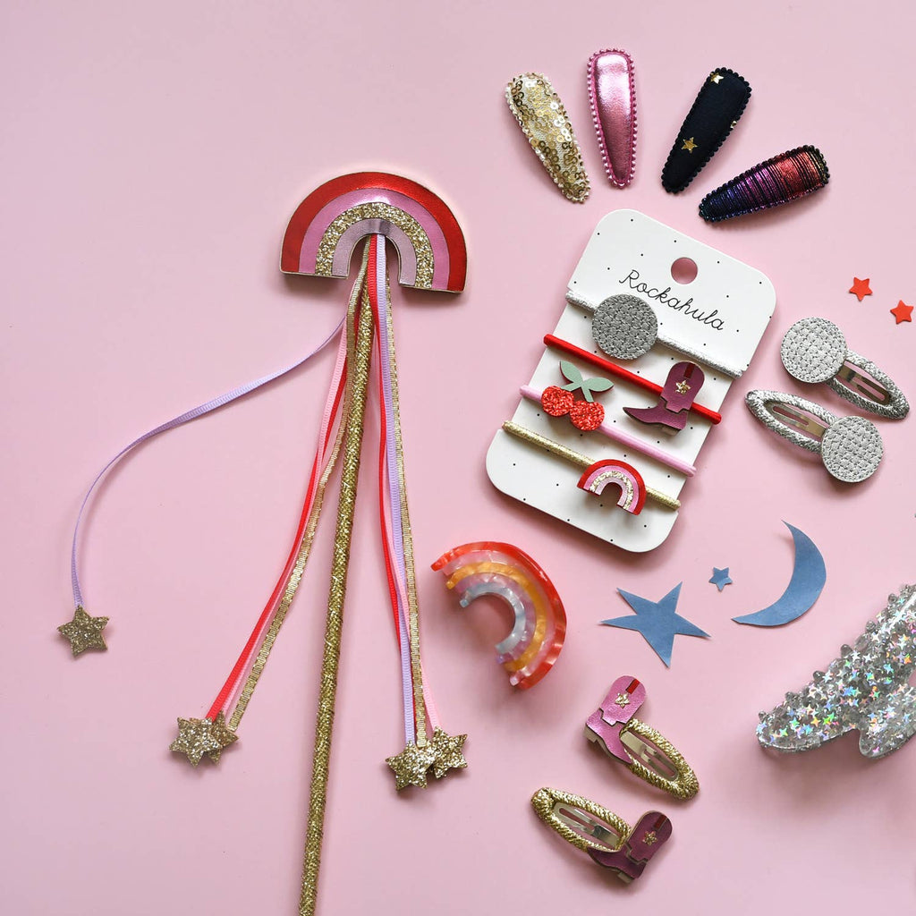 Colorful hair accessories including clips and ribbons on a pink background