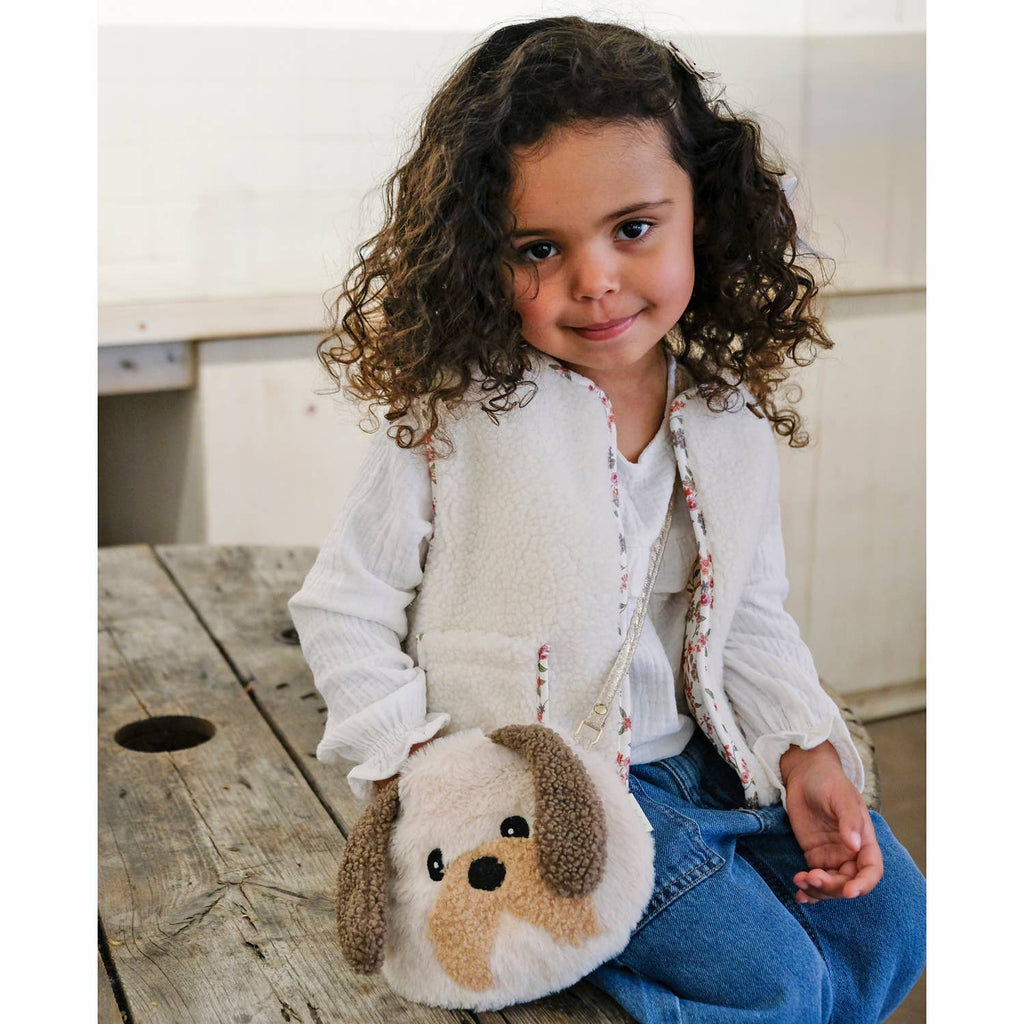 Child holding a plush dog toy on a wooden bench