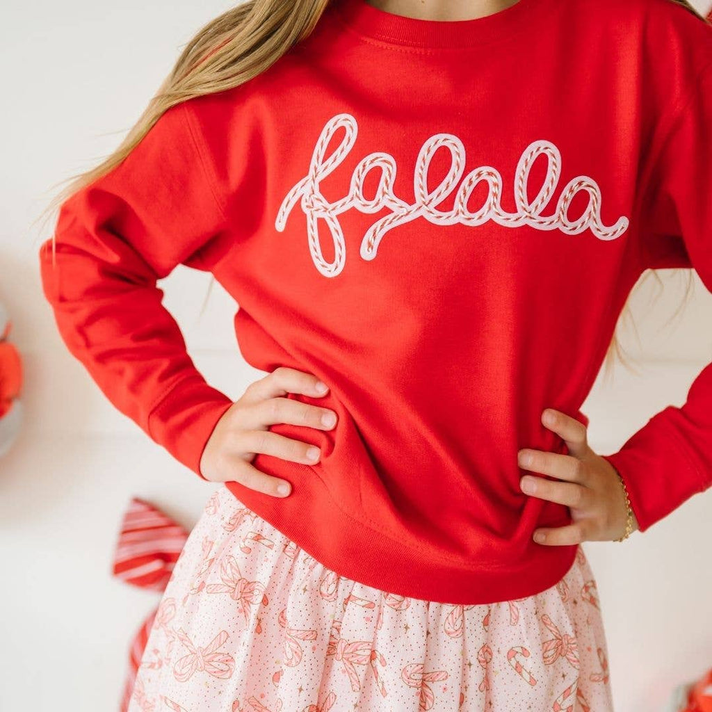 Red sweater with 'falala' text worn by a person, with a blurred background