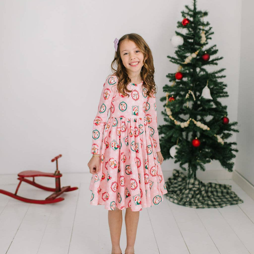 Young girl in a pink dress with Christmas tree decorations in the background