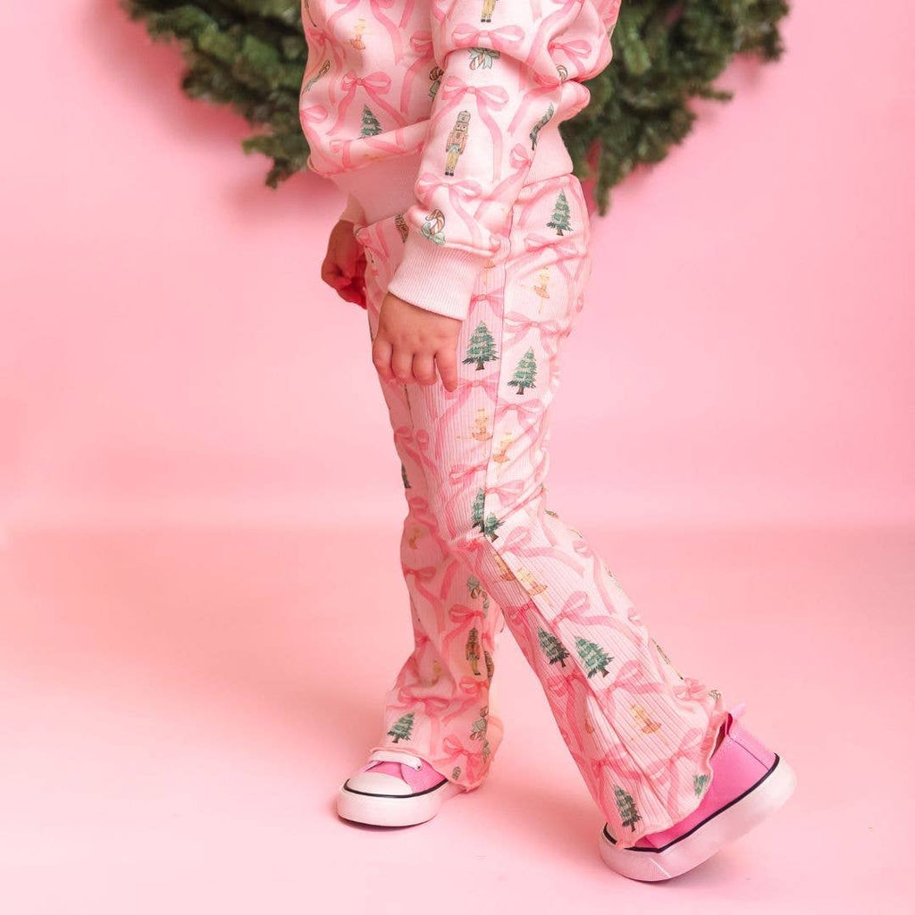 Person wearing pink pajama set with tree pattern on a pink background