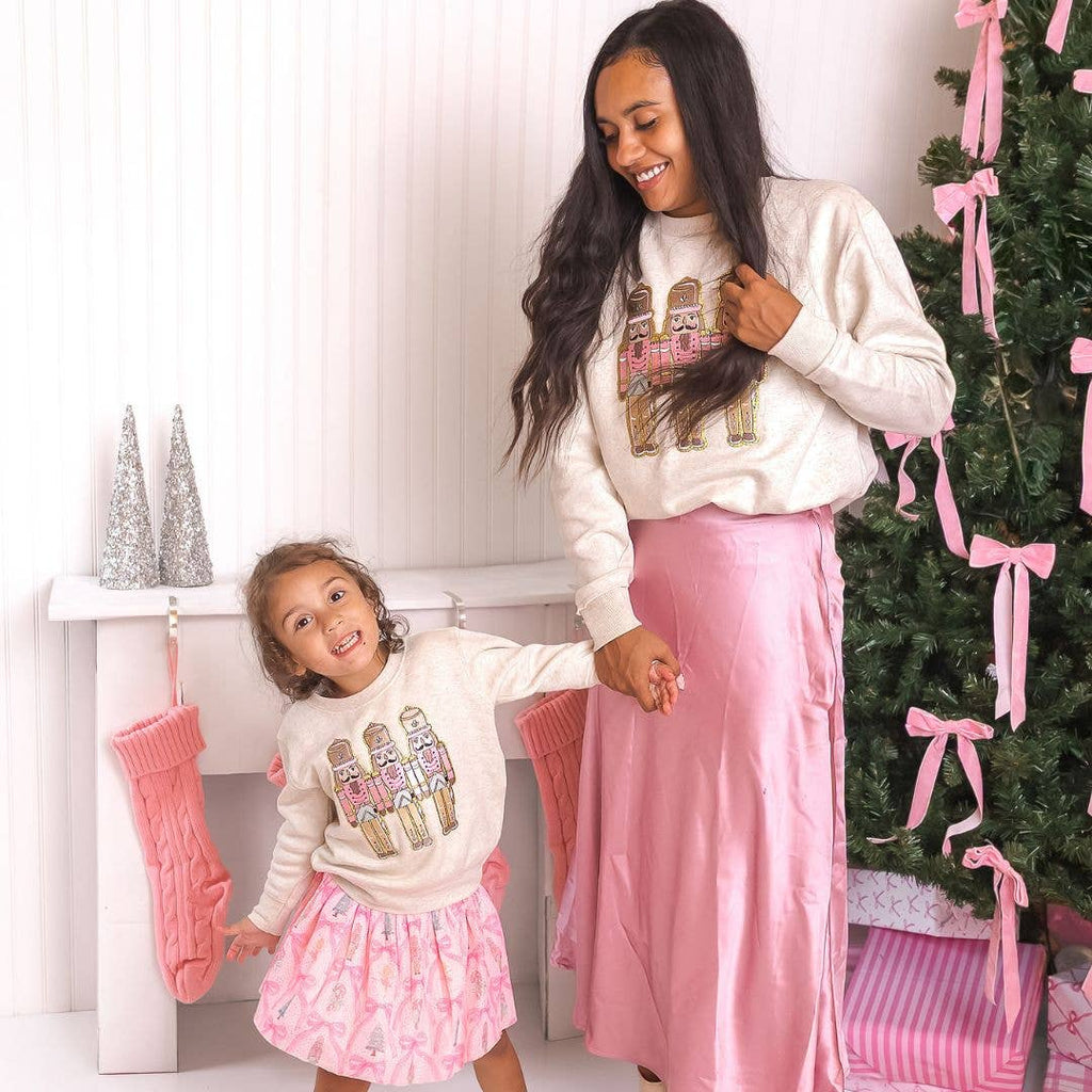 Woman and child in matching outfits standing in front of a decorated Christmas tree.