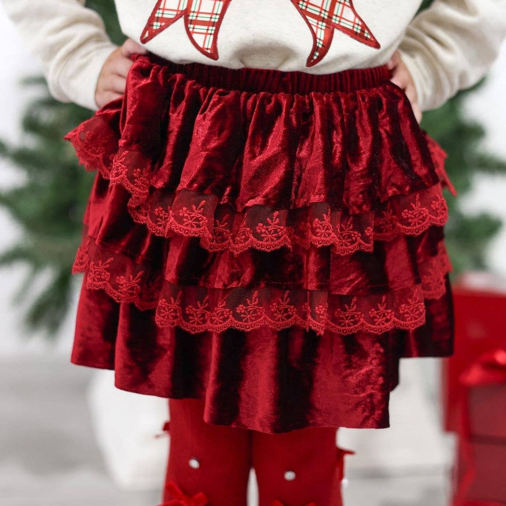 Red tiered skirt worn by a child with a blurred Christmas tree background