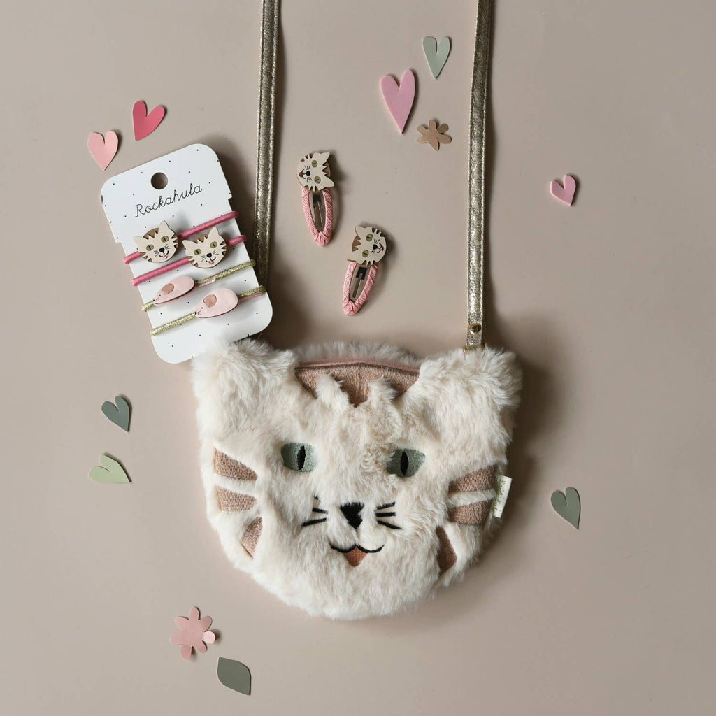 Fluffy cat-shaped handbag with hair accessories on a beige background