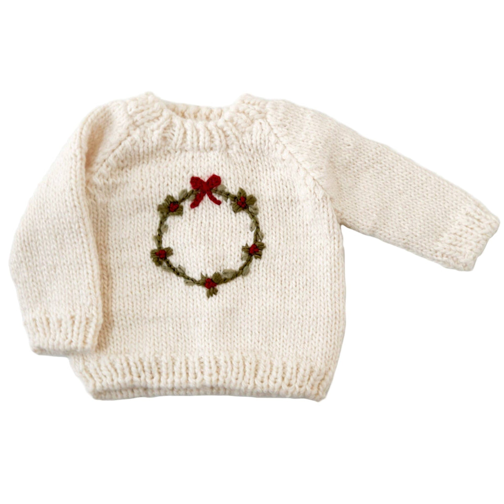 White knitted sweater with a Christmas wreath design on a white background